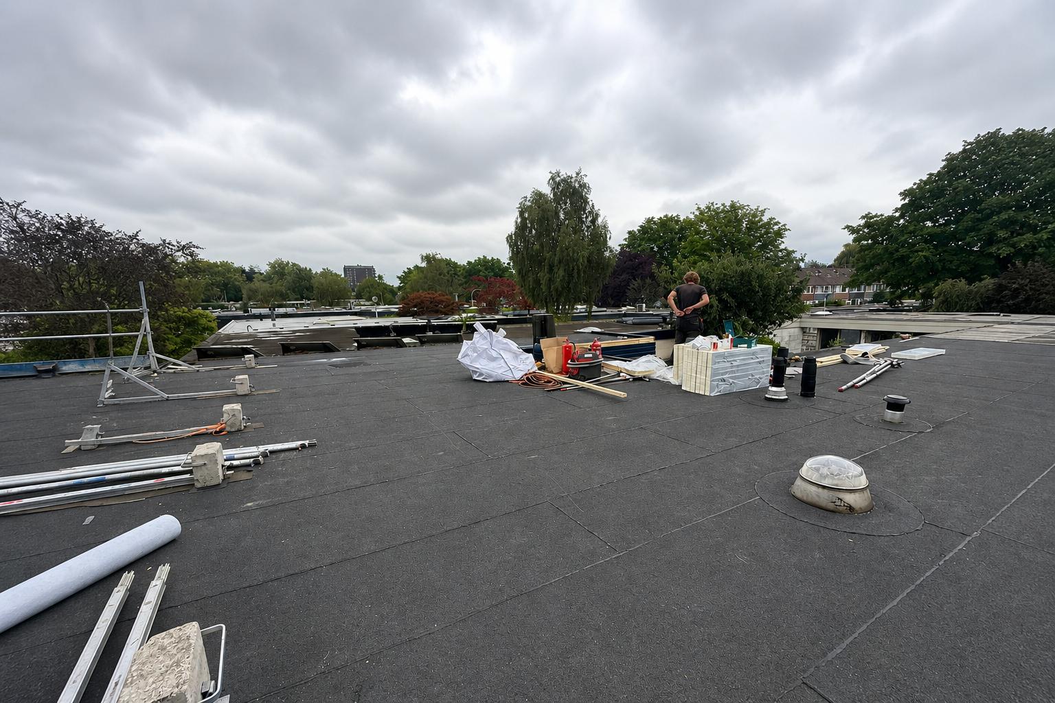 Plat bitumendak tijdens uitvoering: dakdekker, materiaal en gereedschap op het werkvlak; professionele dakbedekking door Nouwen Bouw & Dakservice